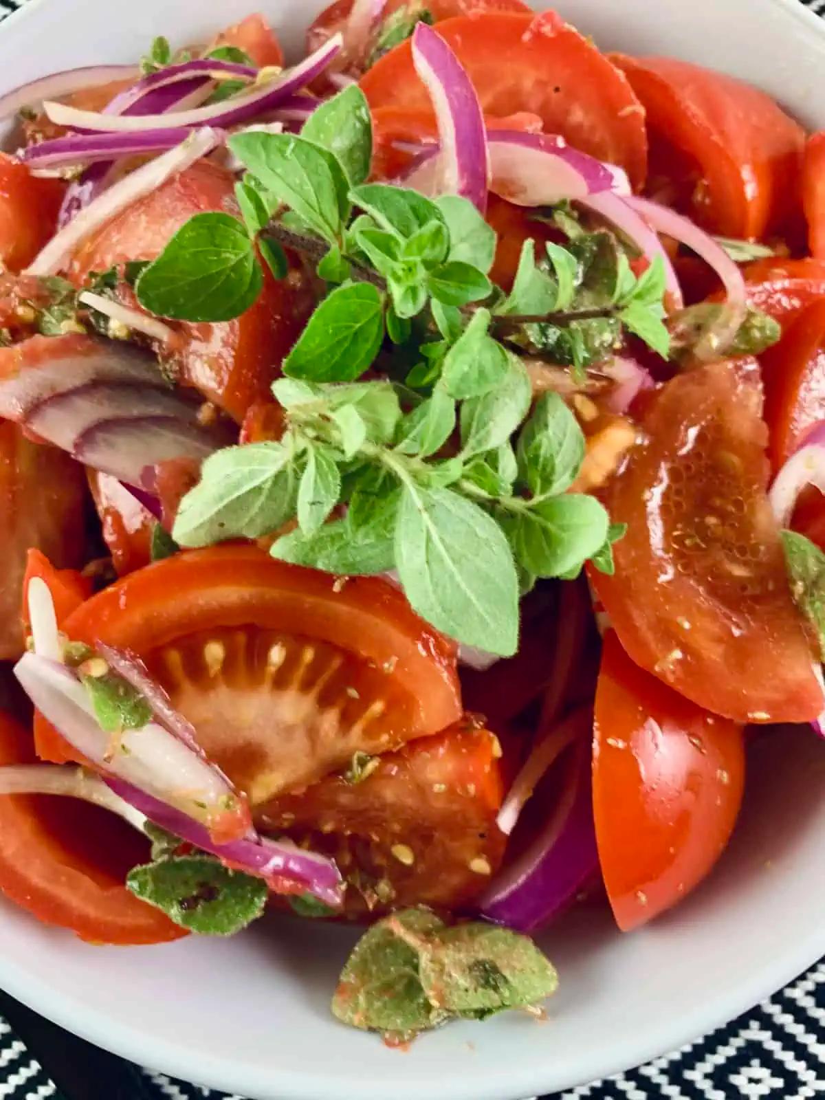 Close up of injera with tomato and onion salad, garnished with fresh herbs