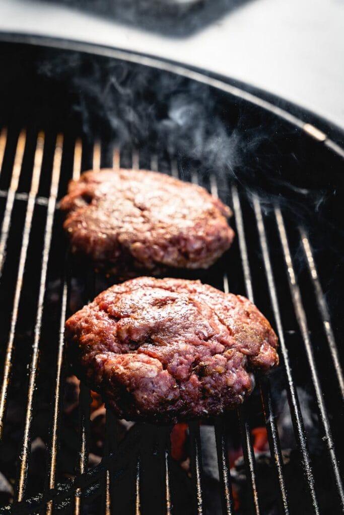 Close-up of a perfectly cooked lamb burger patty sizzling on a grill pan