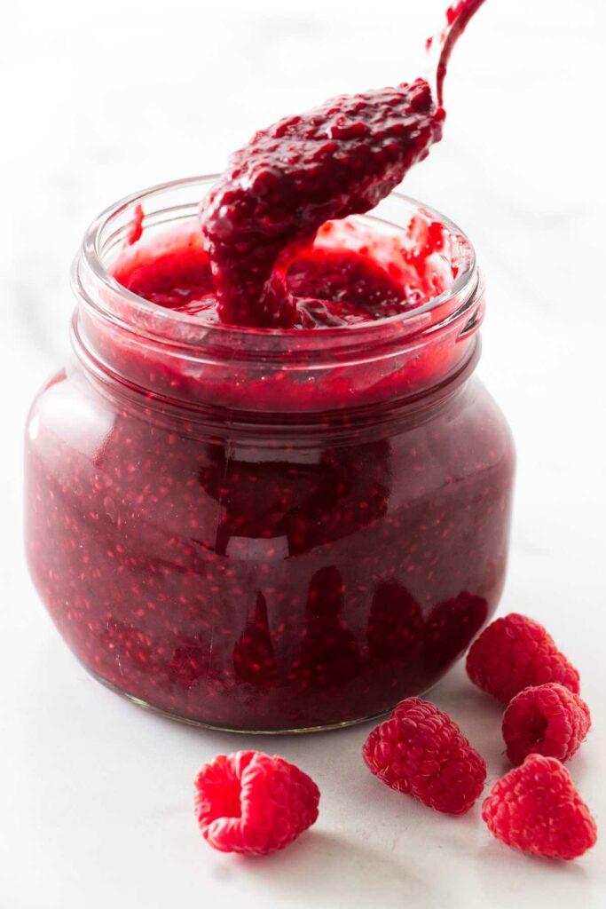 A stack of freshly baked flatbreads next to a jar of lingonberry jam