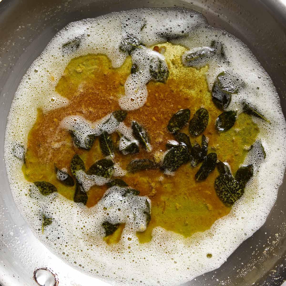 close-up of browned butter in a skillet with sage leaves