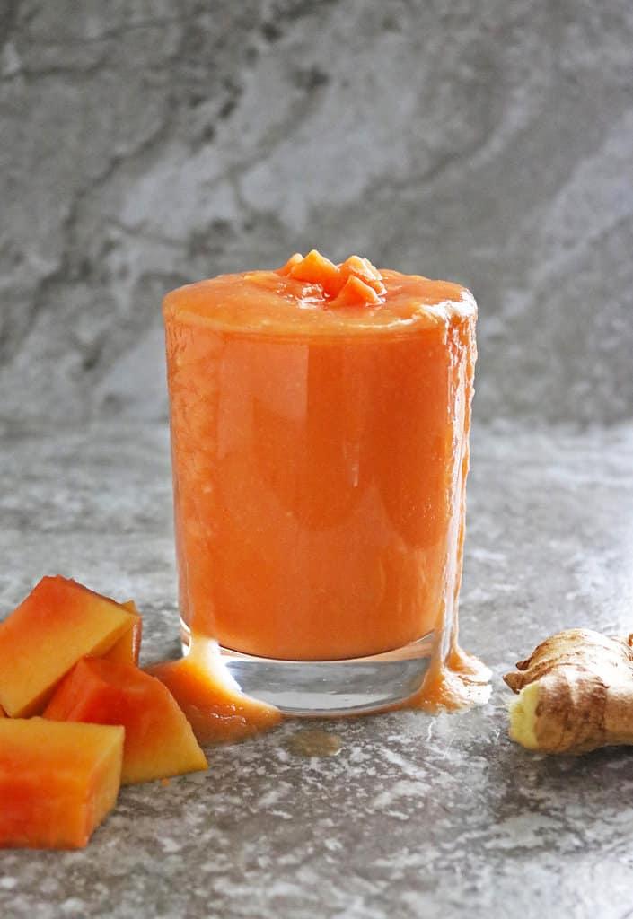 Ingredients for papaya orange ginger smoothie laid out on a wooden table