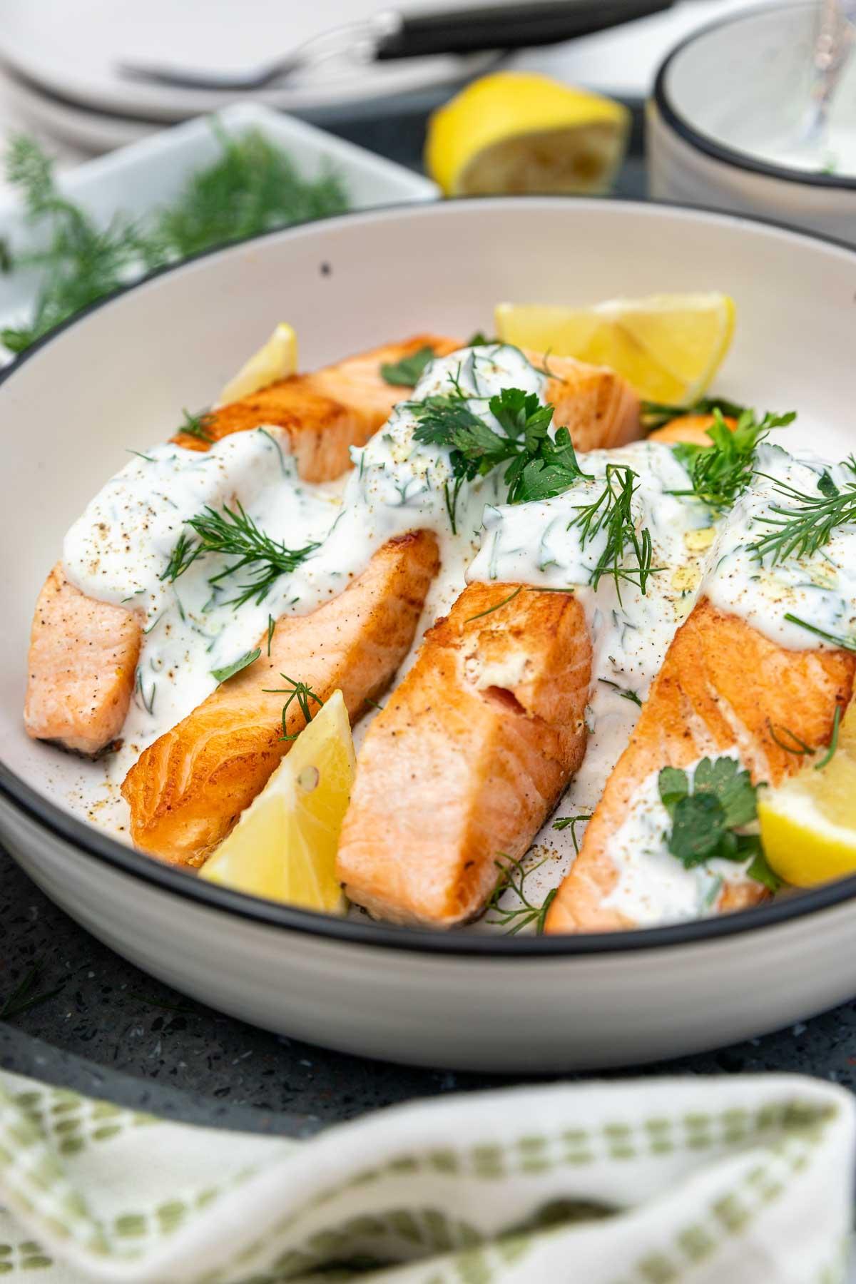 Close-up shot of grilled fish fillets drizzled with creamy dill sauce