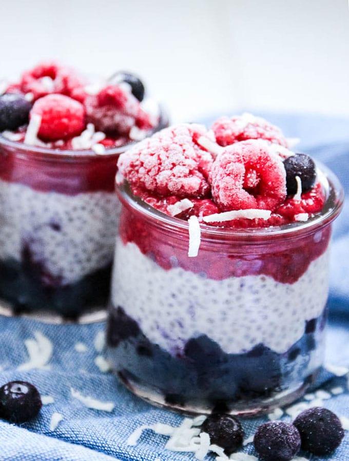close-up of coconut chia seed pudding in glass jars topped with berries