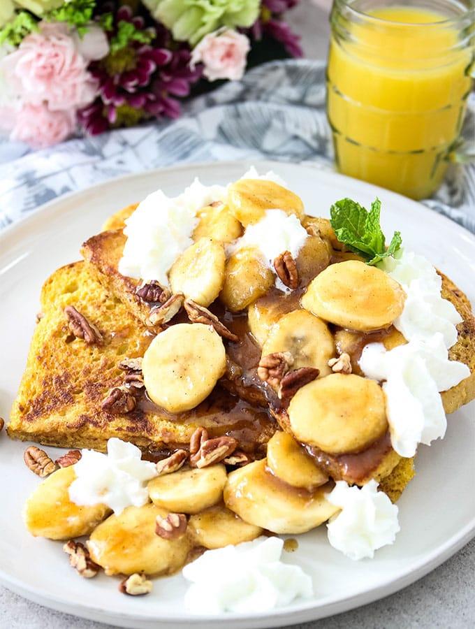 A plate of Banana Foster French Toast, beautifully styled with whipped cream and a sprinkle of cinnamon