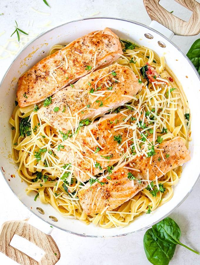 overhead shot of a pot of creamy tuscan salmon pasta with fresh basil garnish
