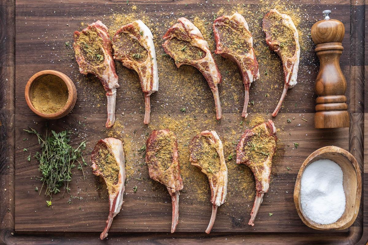 lamb chops being seasoned with spice rub