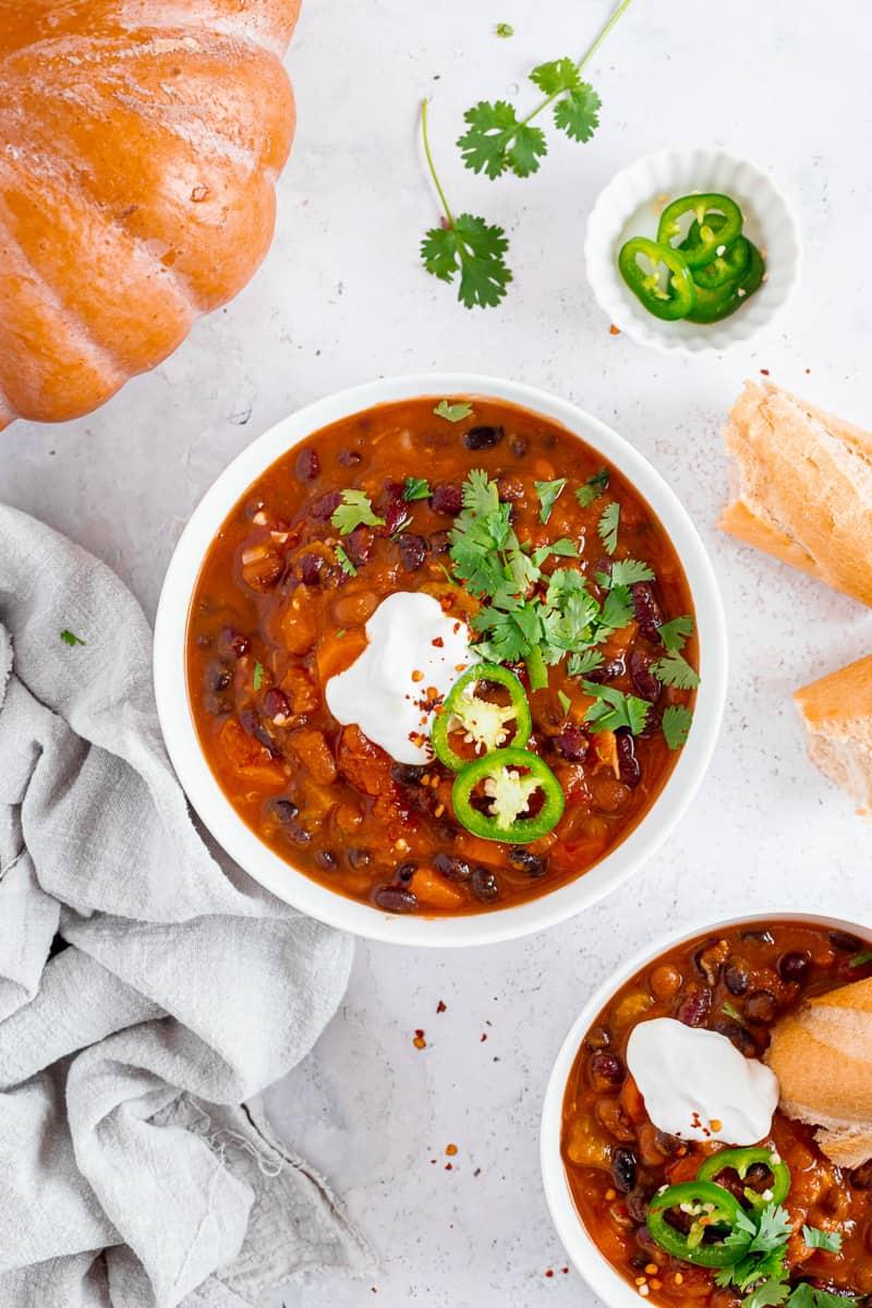 A hearty bowl of pumpkin chili garnished with cilantro and a dollop of sour cream