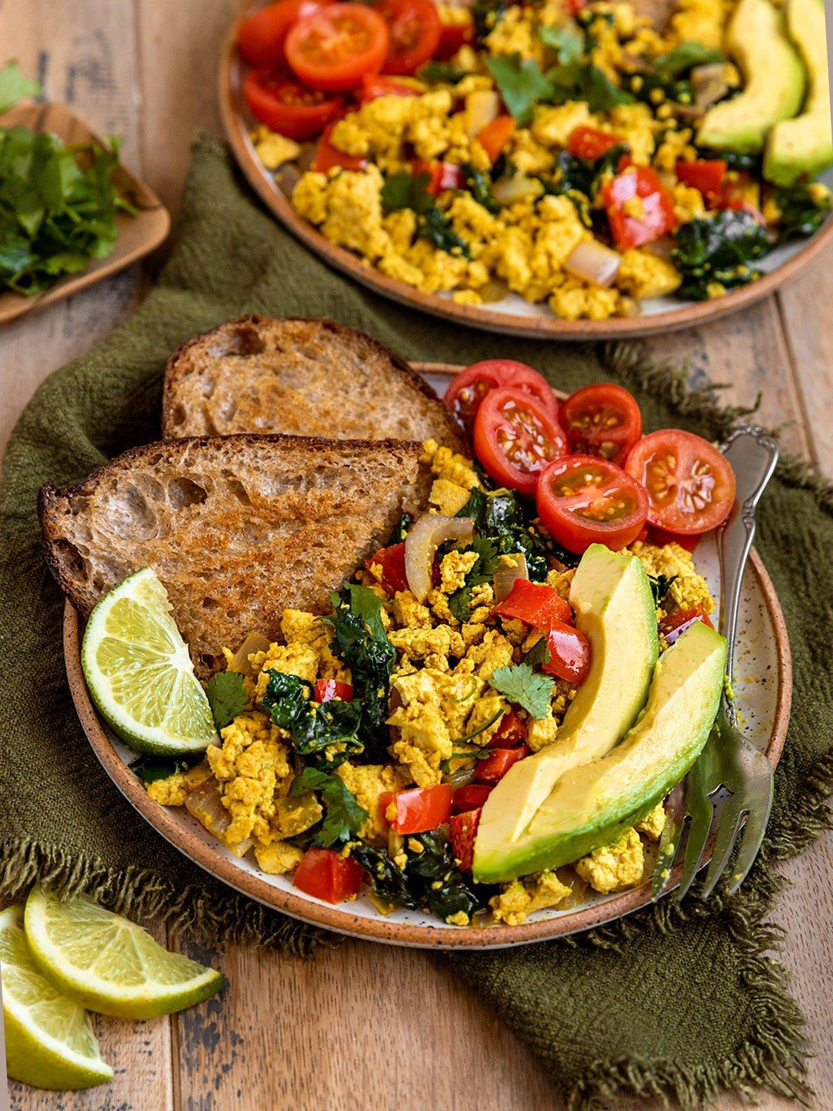 A wide shot of a beautifully plated tofu scramble with mushrooms and thyme, served with toast and a side salad.