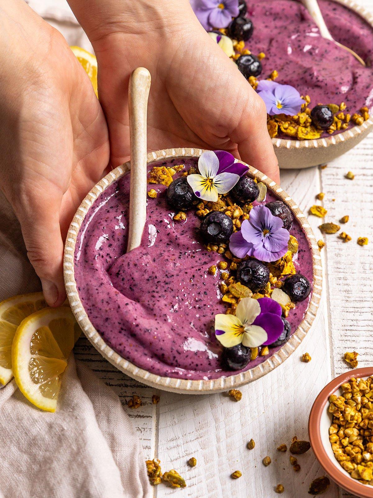Close-up shot of a person enjoying a blueberry lemon smoothie bowl