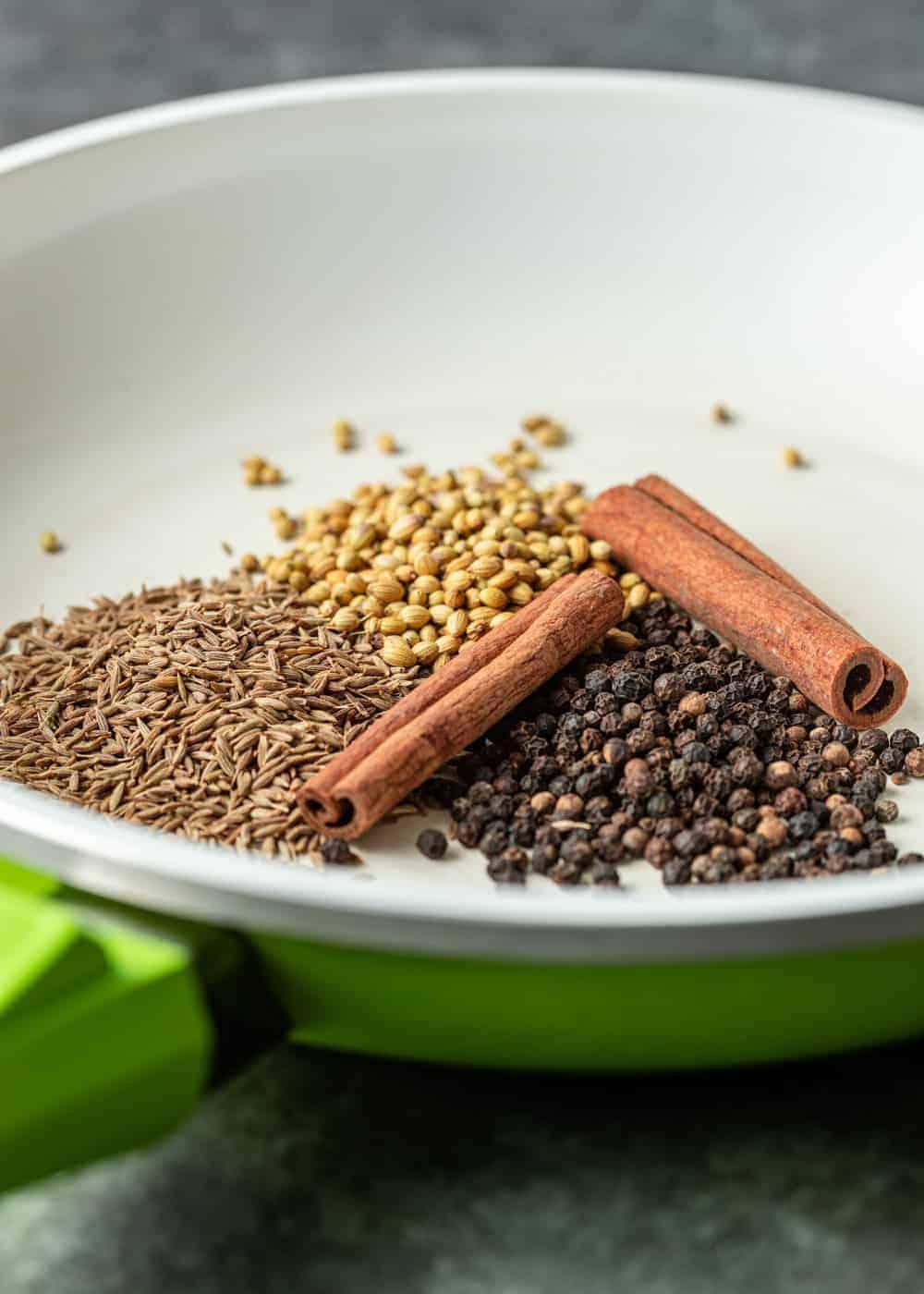 Close up of spices used in the recipe, specifically cinnamon sticks, cumin seeds, and paprika