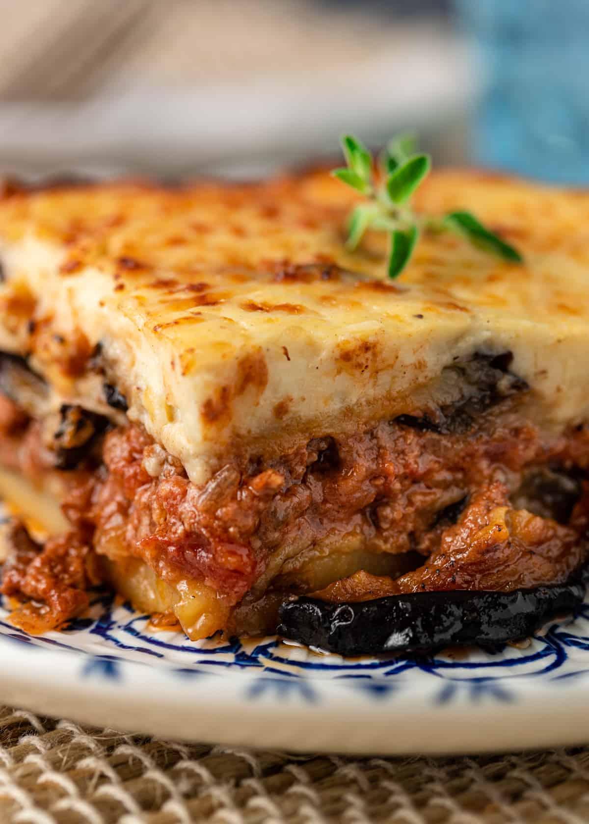 A rustic, close-up shot of Shepherd's Moussaka bubbling in a large ovenproof dish, with a sprinkle of cheese on top