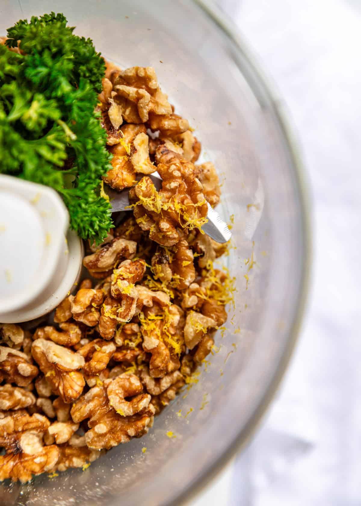 close up of lemon zest being grated over walnuts