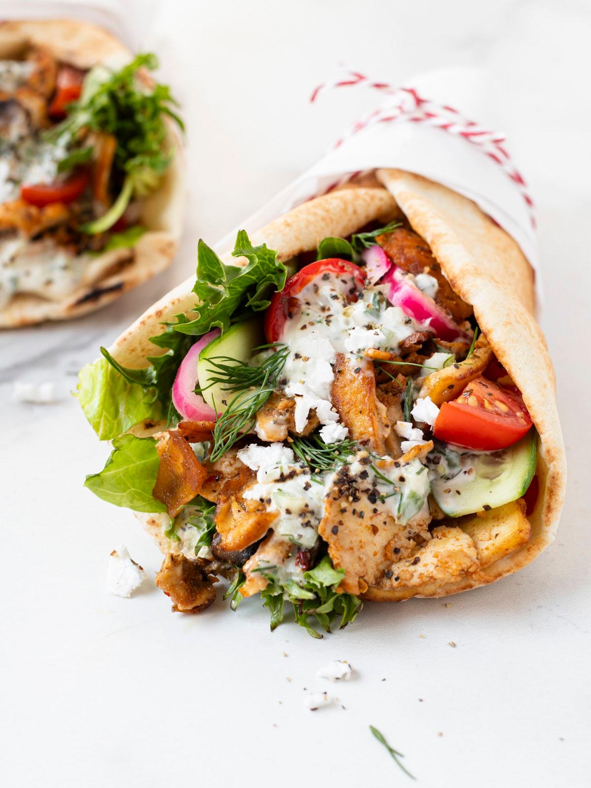 A bowl of gyro spiced tofu scramble topped with fresh herbs and served with pita bread and tzatziki sauce.