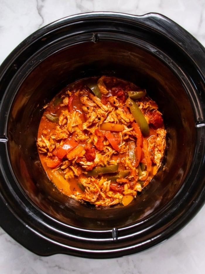 slow cooker filled with chicken, bell peppers, onions, and salsa
