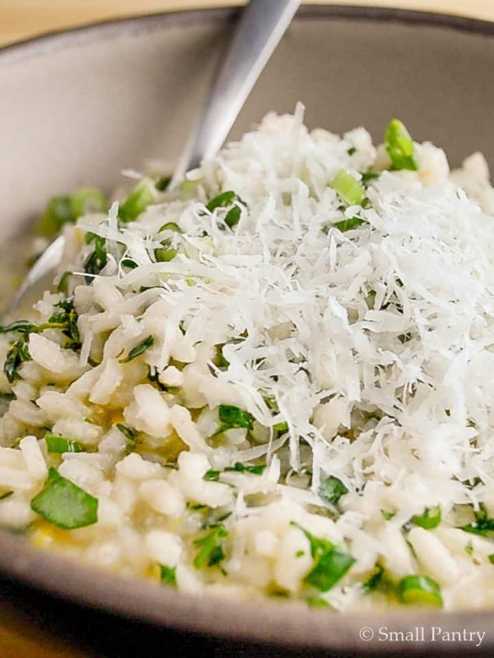 Close-up of a plate of steamed Arborio rice, garnished with Parmesan and fresh herbs