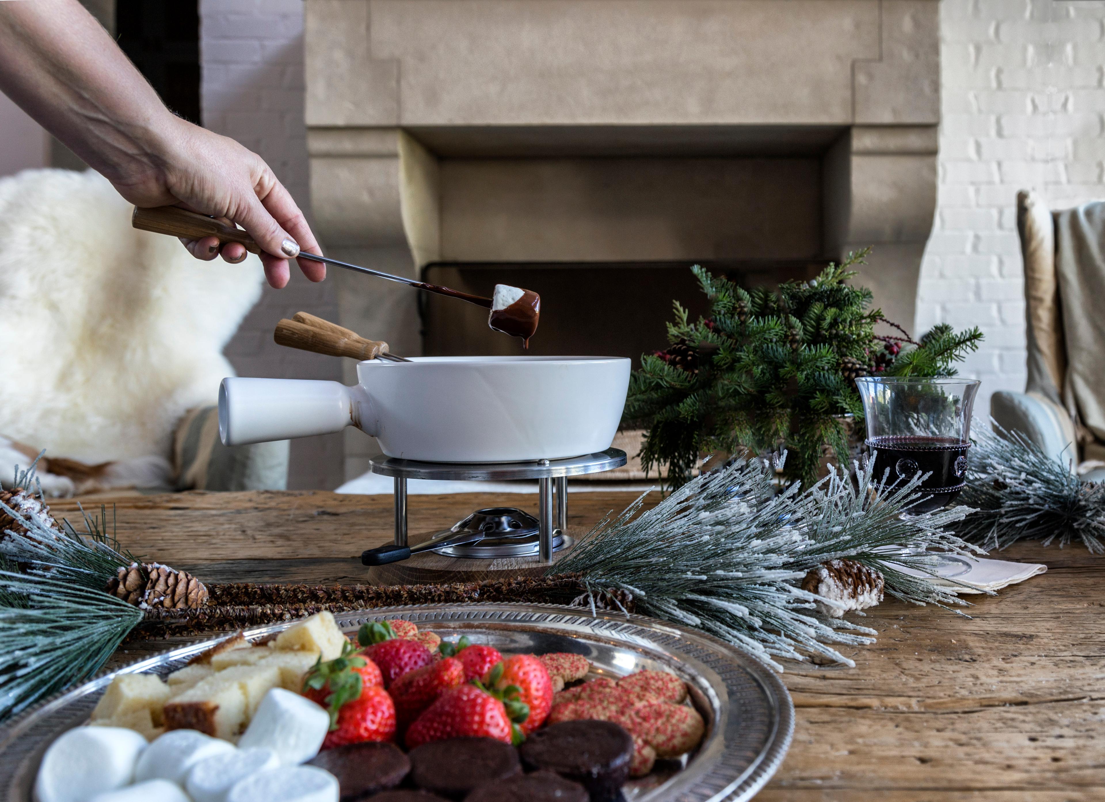 group of friends laughing and dipping various items into a chocolate pistachio fondue pot