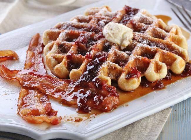waffle iron with lingonberry-maple syrup waffles cooking inside, steam rising