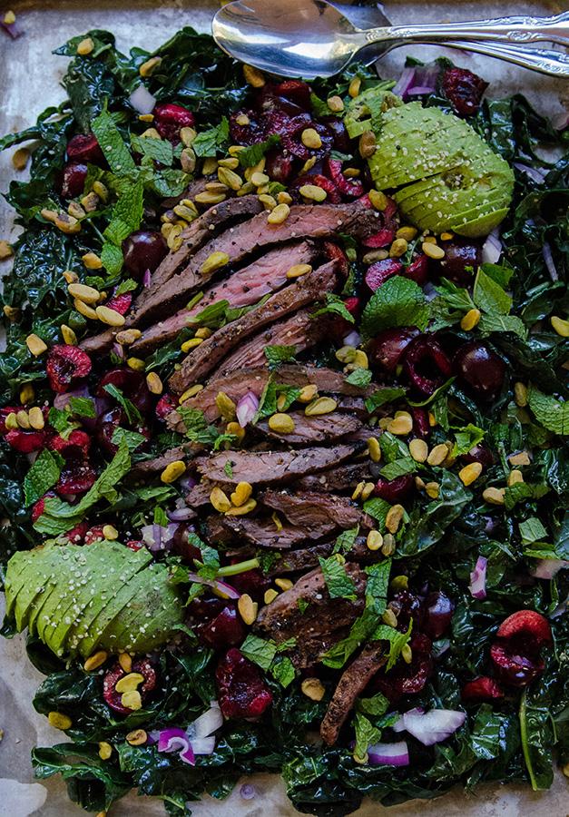 Close-up shot of a perfectly seared steak on a bed of massaged kale