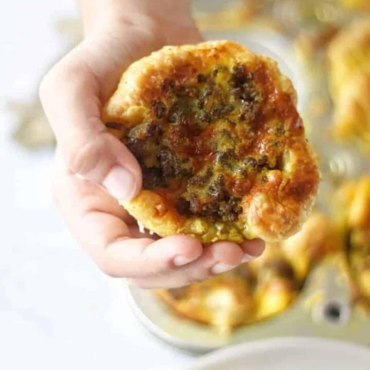 Close-up shot of a golden-brown Bobotie in a skillet, next to a plate of muffins