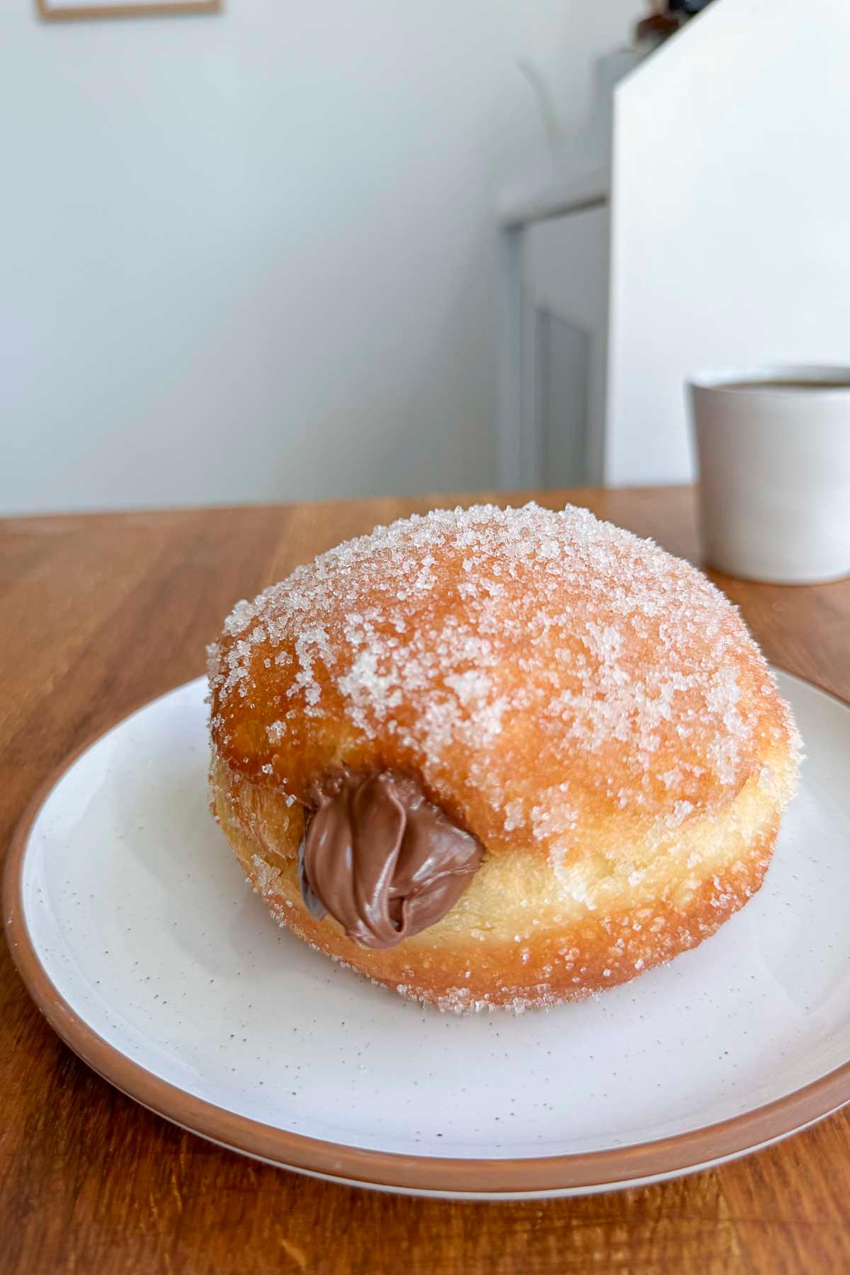 Close-up shot of golden-brown Nutella-stuffed churros donuts dusted with powdered sugar, arranged on a parchment-lined baking sheet.