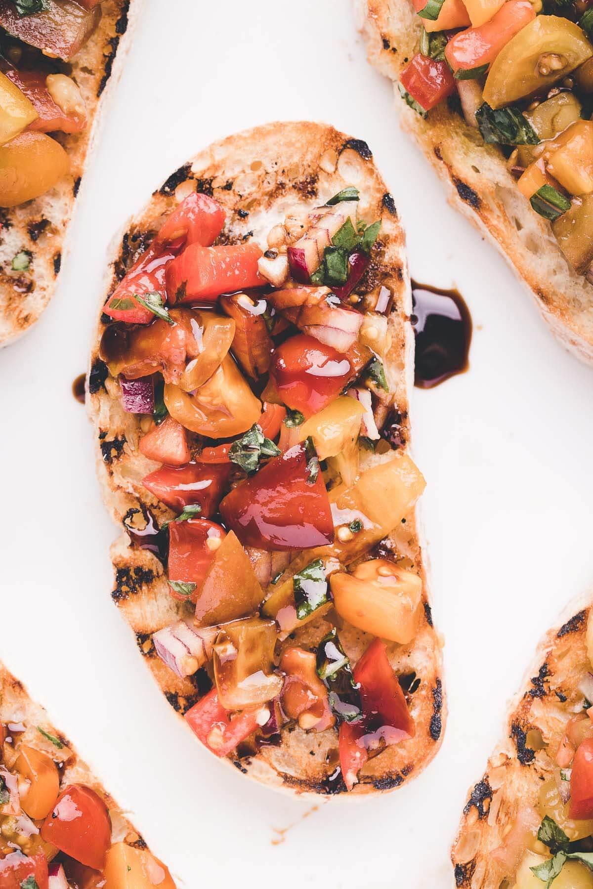 A platter of bruschetta with brie, balsamic glaze, and fresh basil.