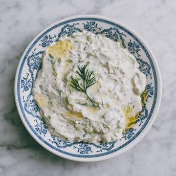 A bowl of fresh tzatziki sauce with a spoon, close up