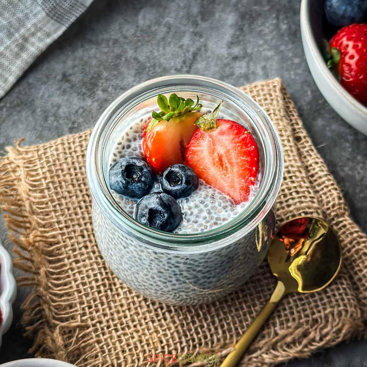 Overhead shot of a glass bowl filled with layered chia pudding and corn, topped with fresh berries