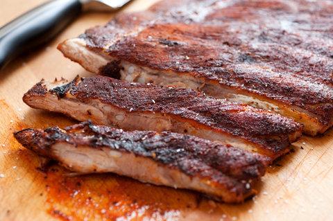 Close-up shot of smoked ribs being sliced, with Tintern and chive cream cheese in the background