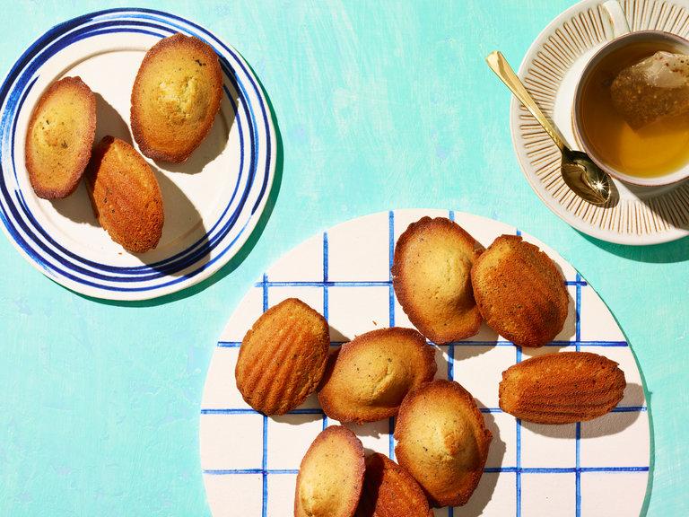 A rustic wooden table with a plate of Earl Grey madeleines and a cup of tea