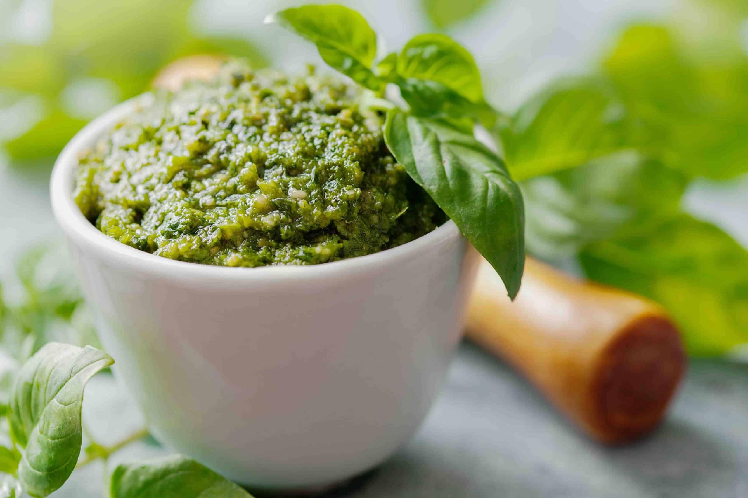 A bowl of basil and pistachio pesto garnished with fresh basil and pistachios