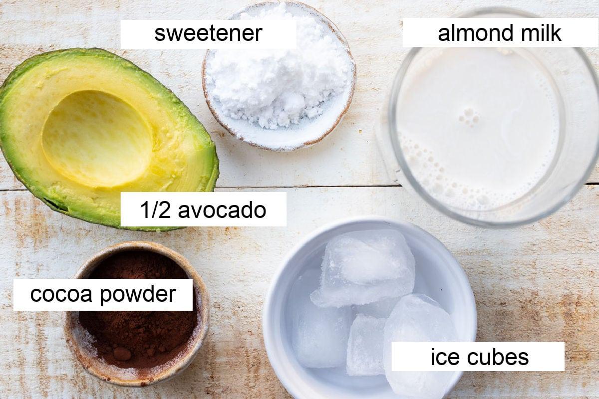 A bowl of ingredients: cocoa powder, avocado, milk, sweetener