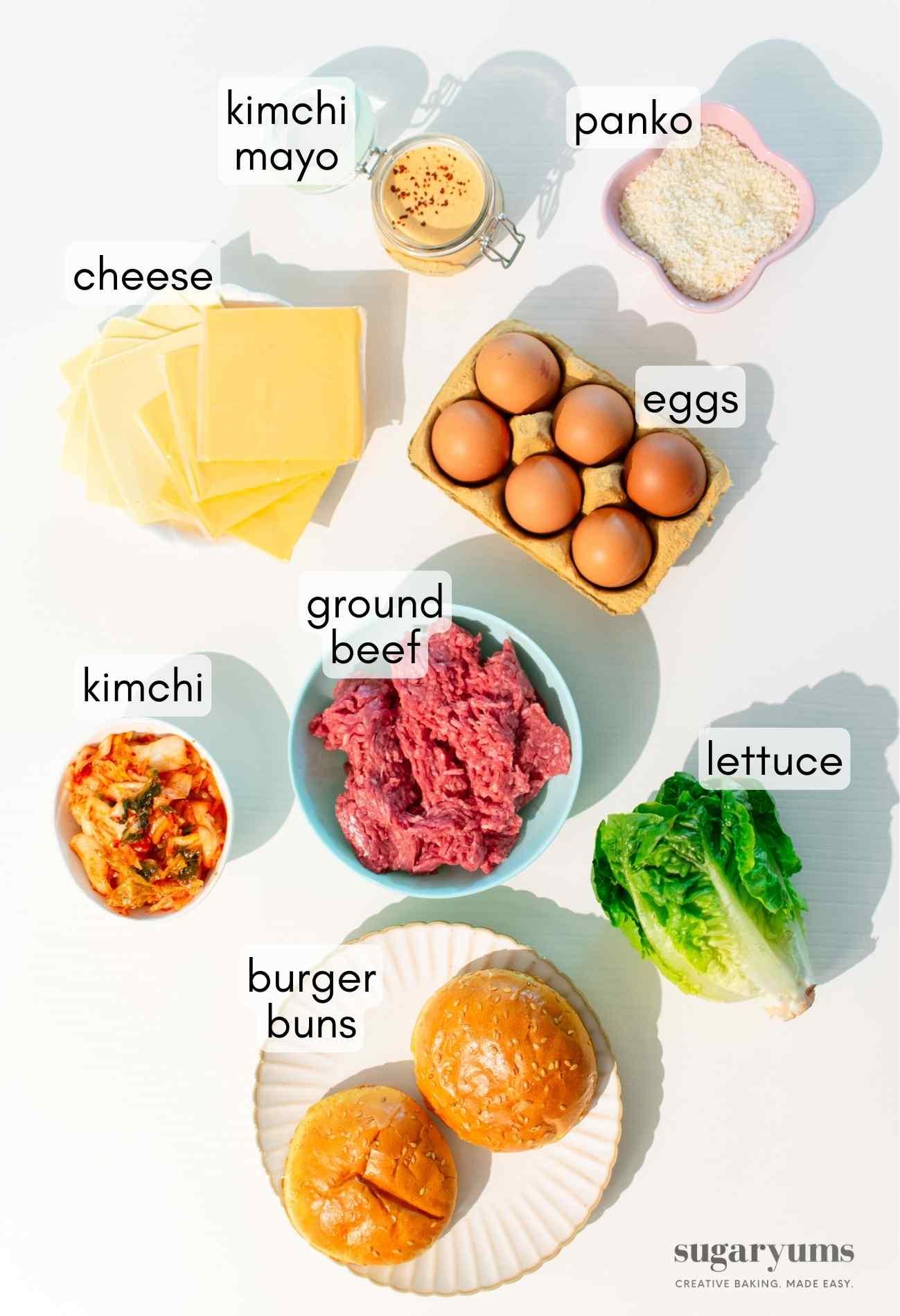 Overhead shot of ingredients laid out for making a kimchi burger, including ground beef, kimchi, buns, and condiments