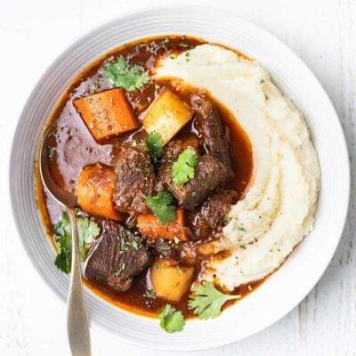 Delicious close-up of a steaming bowl of chili-garlic beef stew with crusty bread