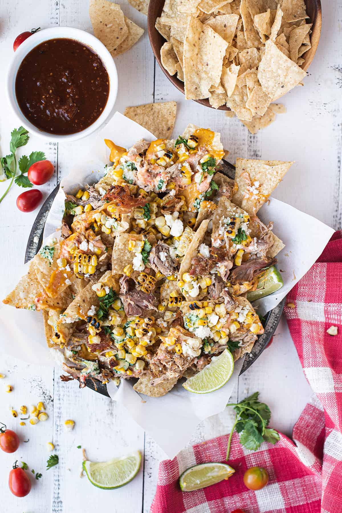A platter of pulled pork nachos with chipotle BBQ sauce, garnished with cilantro and green onions