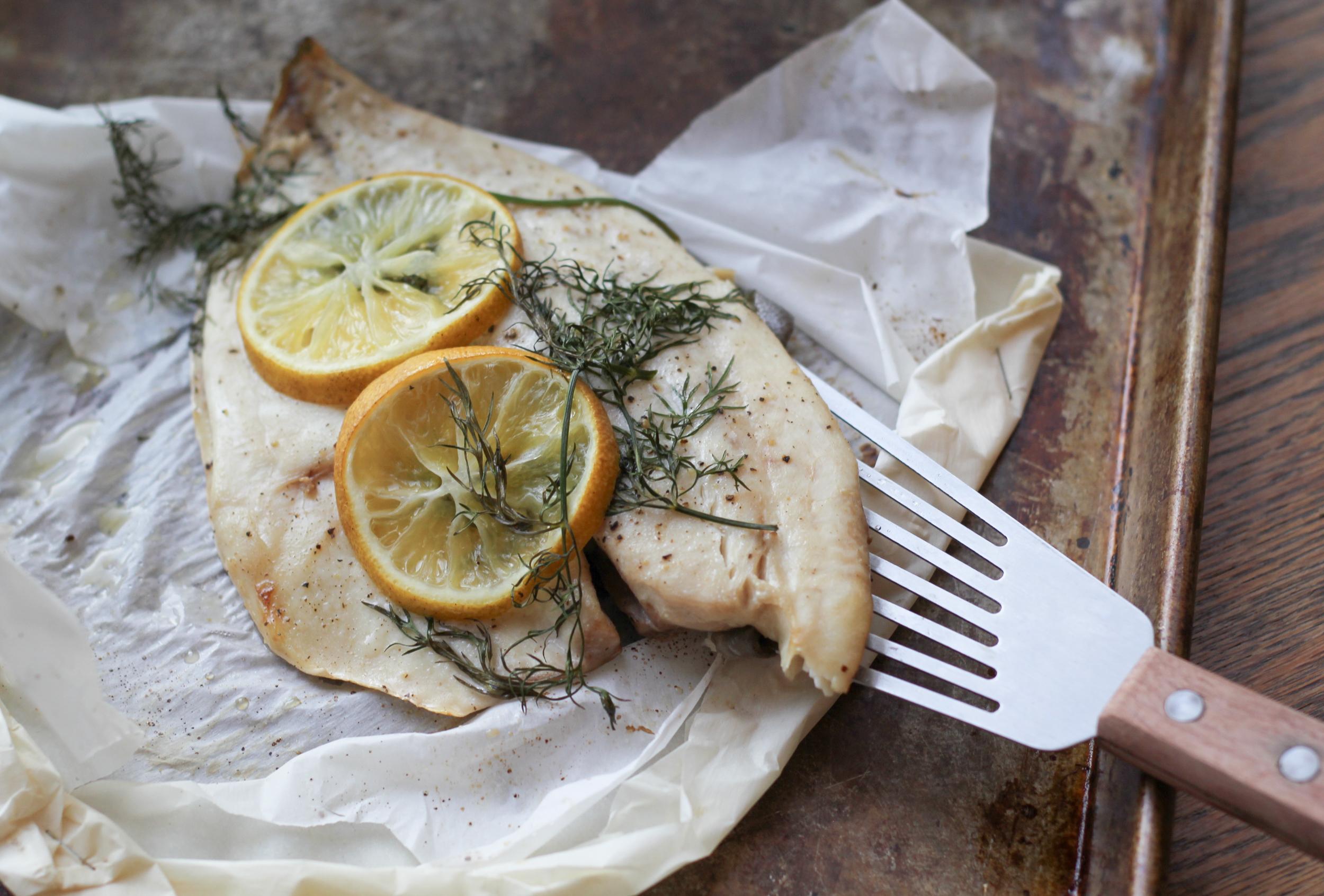 close-up shot of a fork flaking off a piece of steamed fish, revealing its moist texture