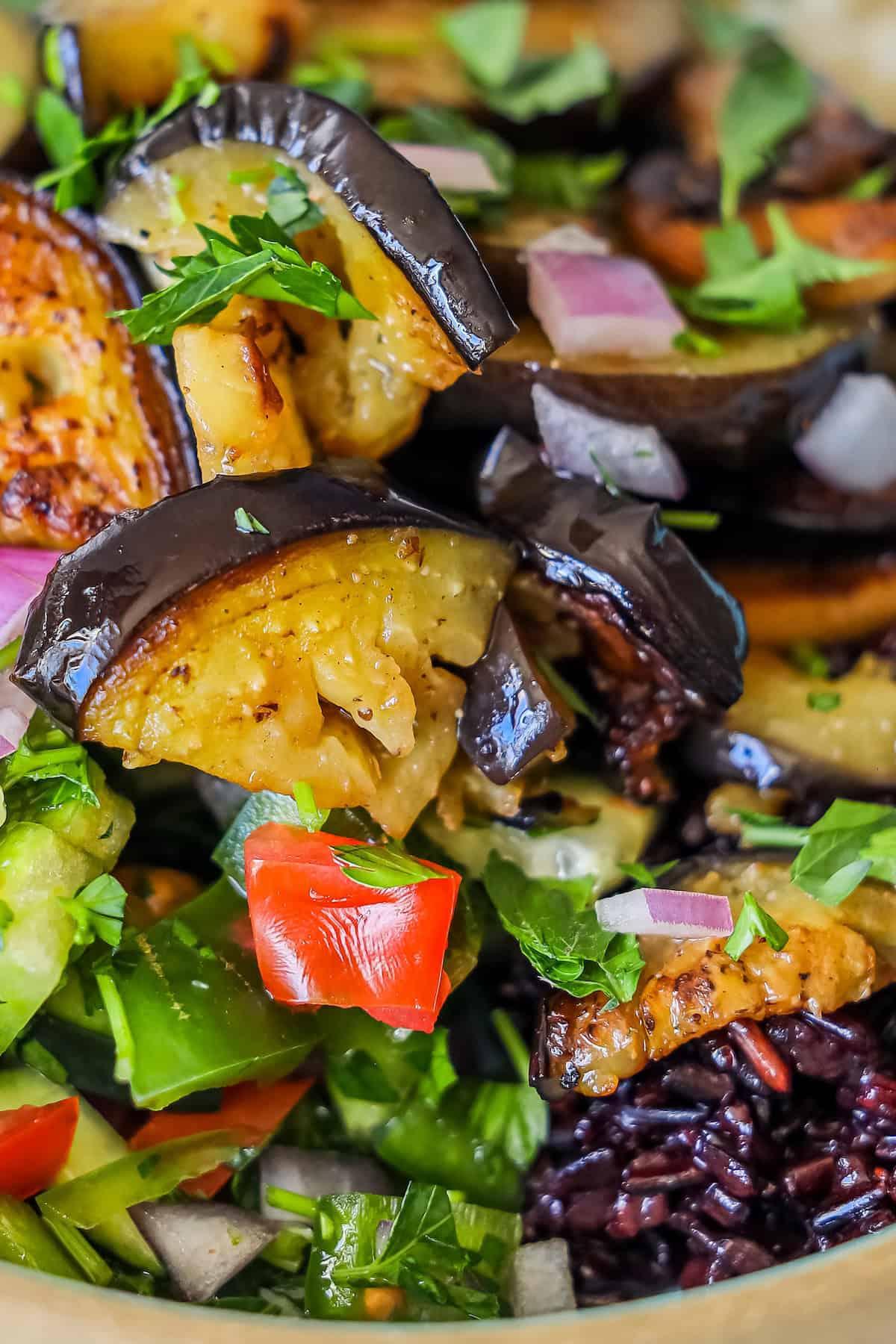 Close-up shot of the fried eggplant and tahini dressing drizzled over the grain bowl