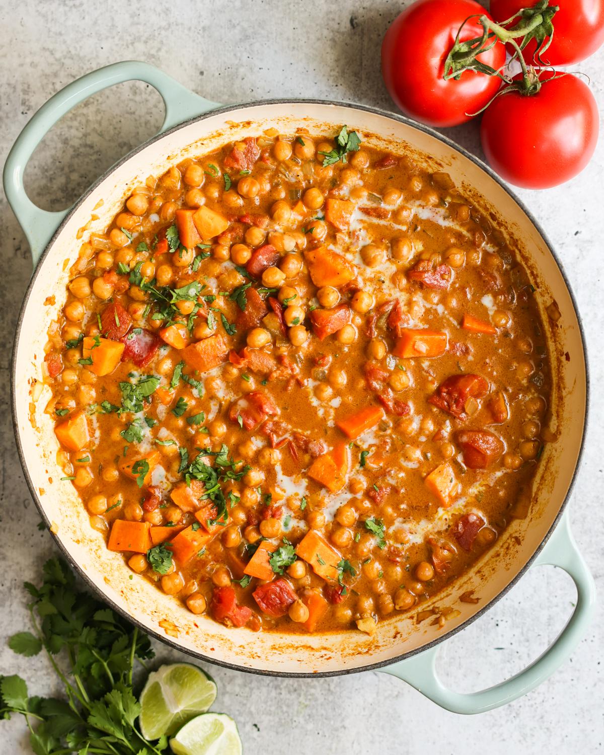 A vibrant, close-up shot of sweet potato and chickpea curry in a bowl, garnished with fresh cilantro and a squeeze of lime.