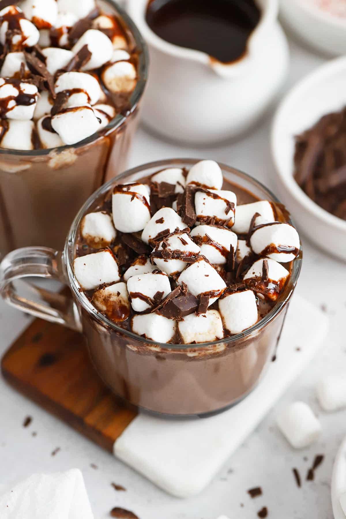 A steaming mug of hot chocolate with cashew milk, marshmallows, and chocolate shavings