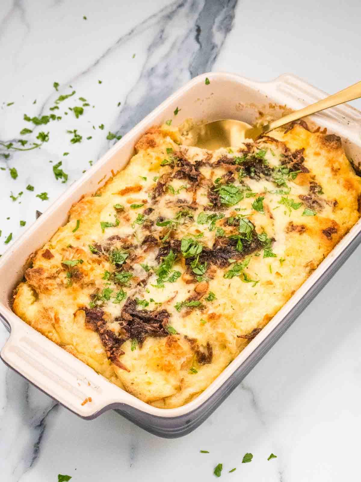 Close-up shot of Chili Cheese Fries Stale Bread Pudding, showing the cheesy, chili-laden bread pudding in a baking dish