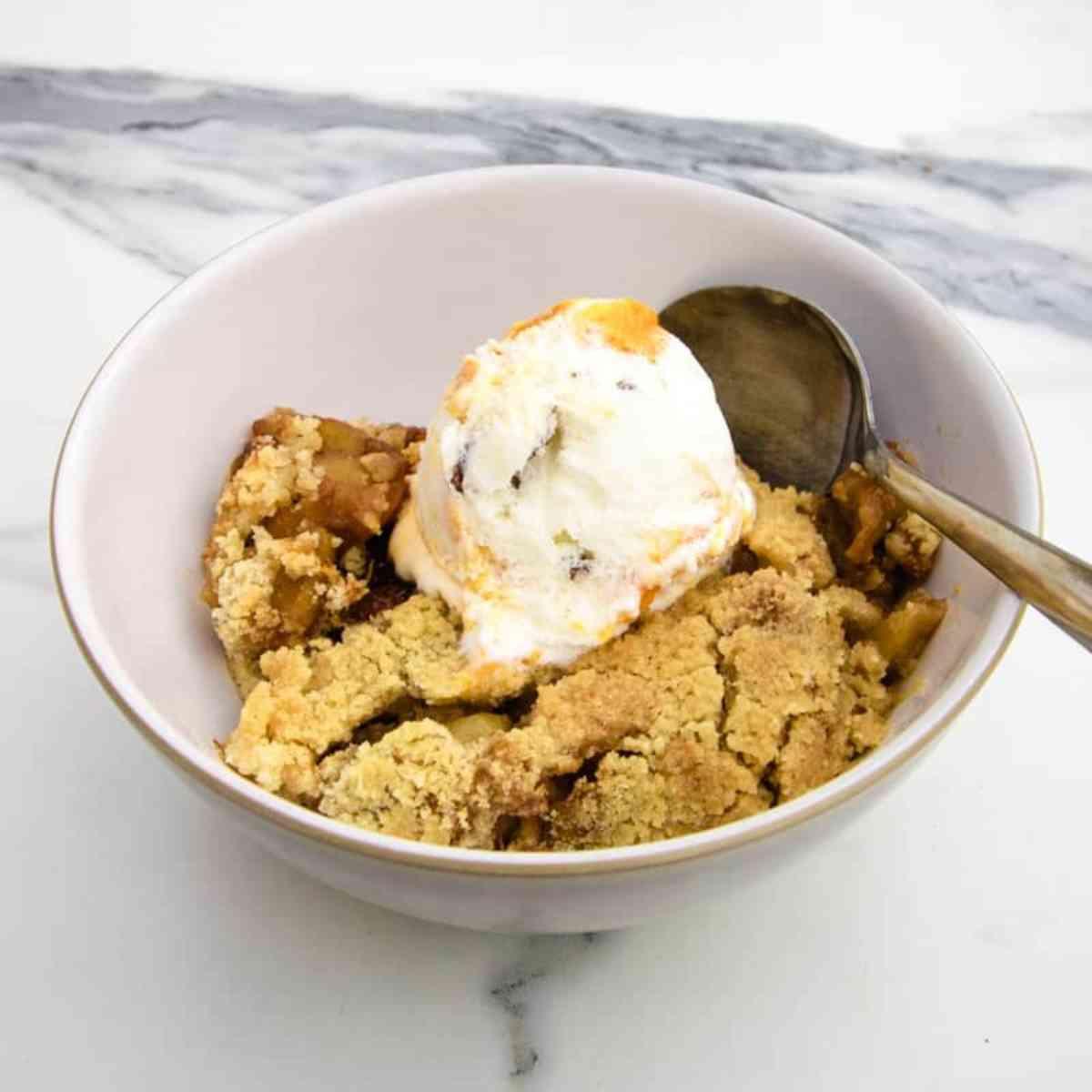 close-up shot of plantain and apple crumble with a scoop of vanilla ice cream