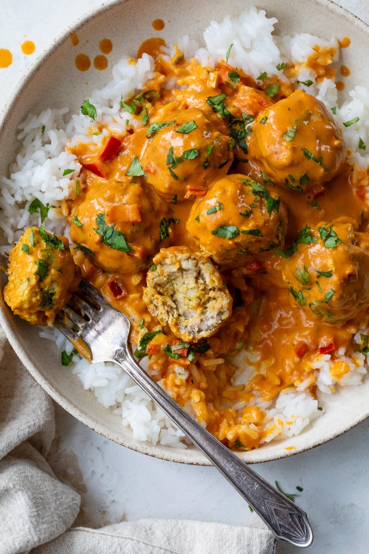 close up of curried coconut plant-based meatballs in a pan with rice