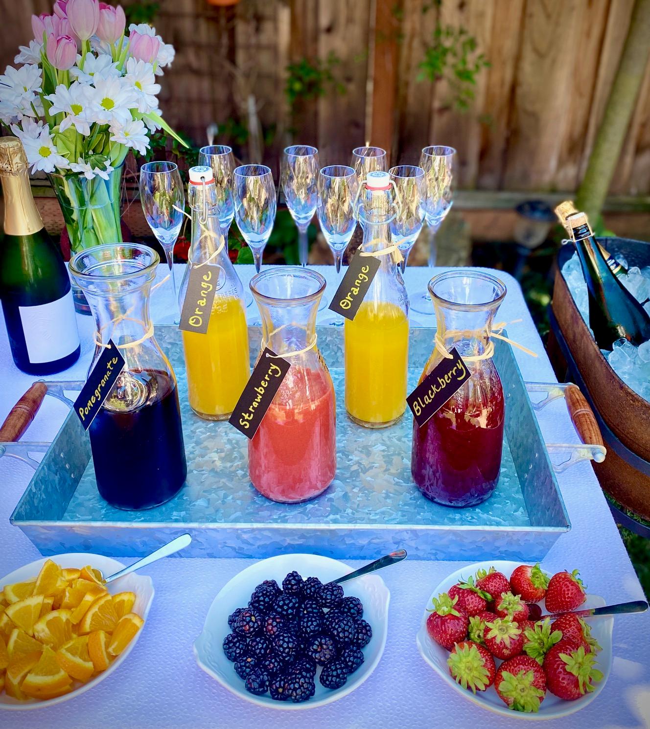 overhead shot of a mimosa bar setup with various juice options and fresh fruit