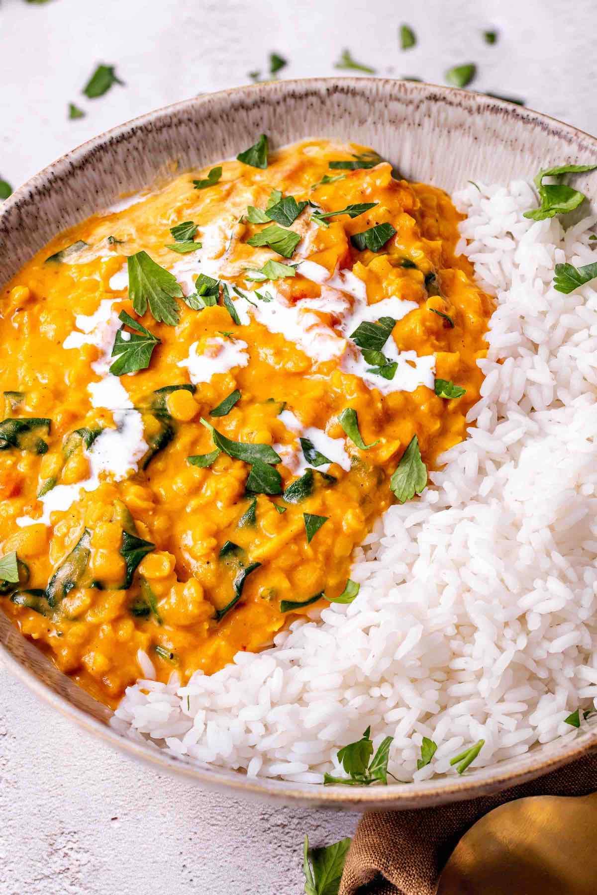 A steaming bowl of healthy yellow lentil dal with rice and cilantro garnish