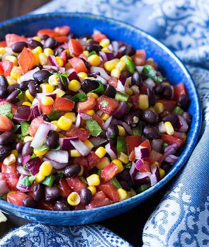 A person adding fresh cilantro to the black bean salsa