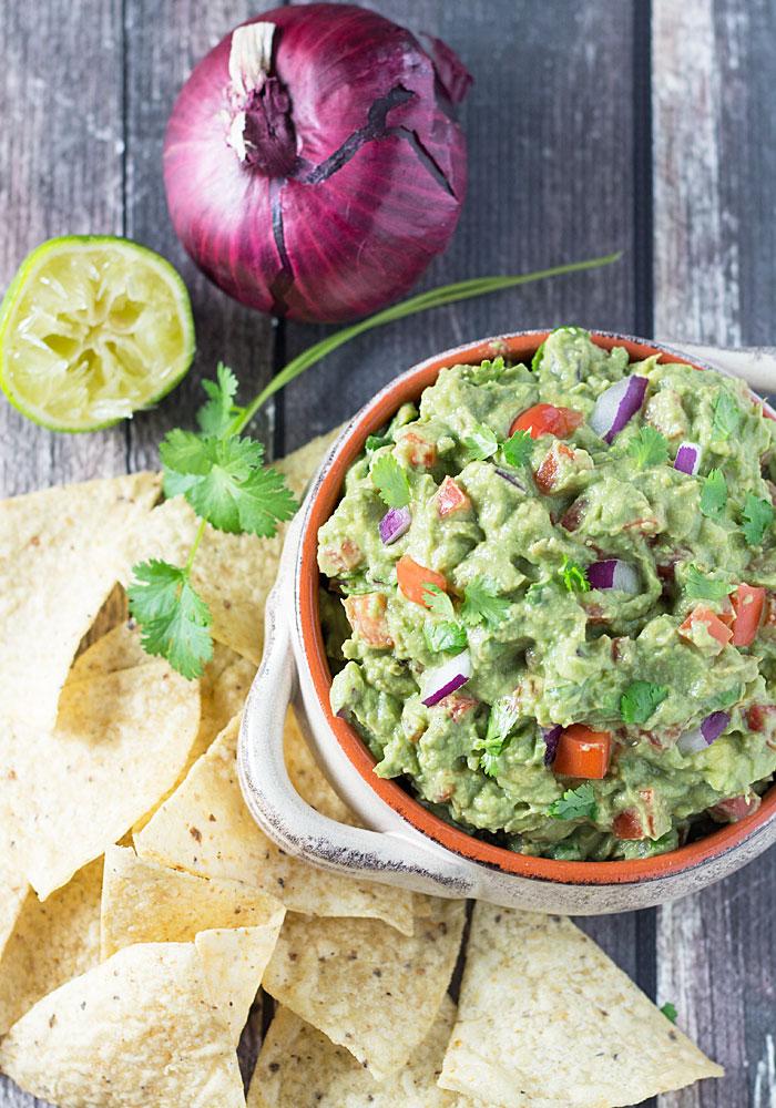 Close-up shot of a bowl of creamy guacamole with a swirl of yogurt