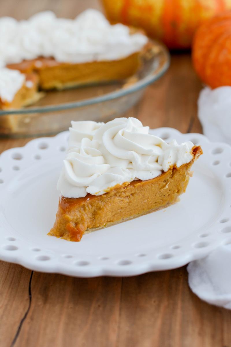 Close up shot of a slice of pumpkin pie with whipped cream