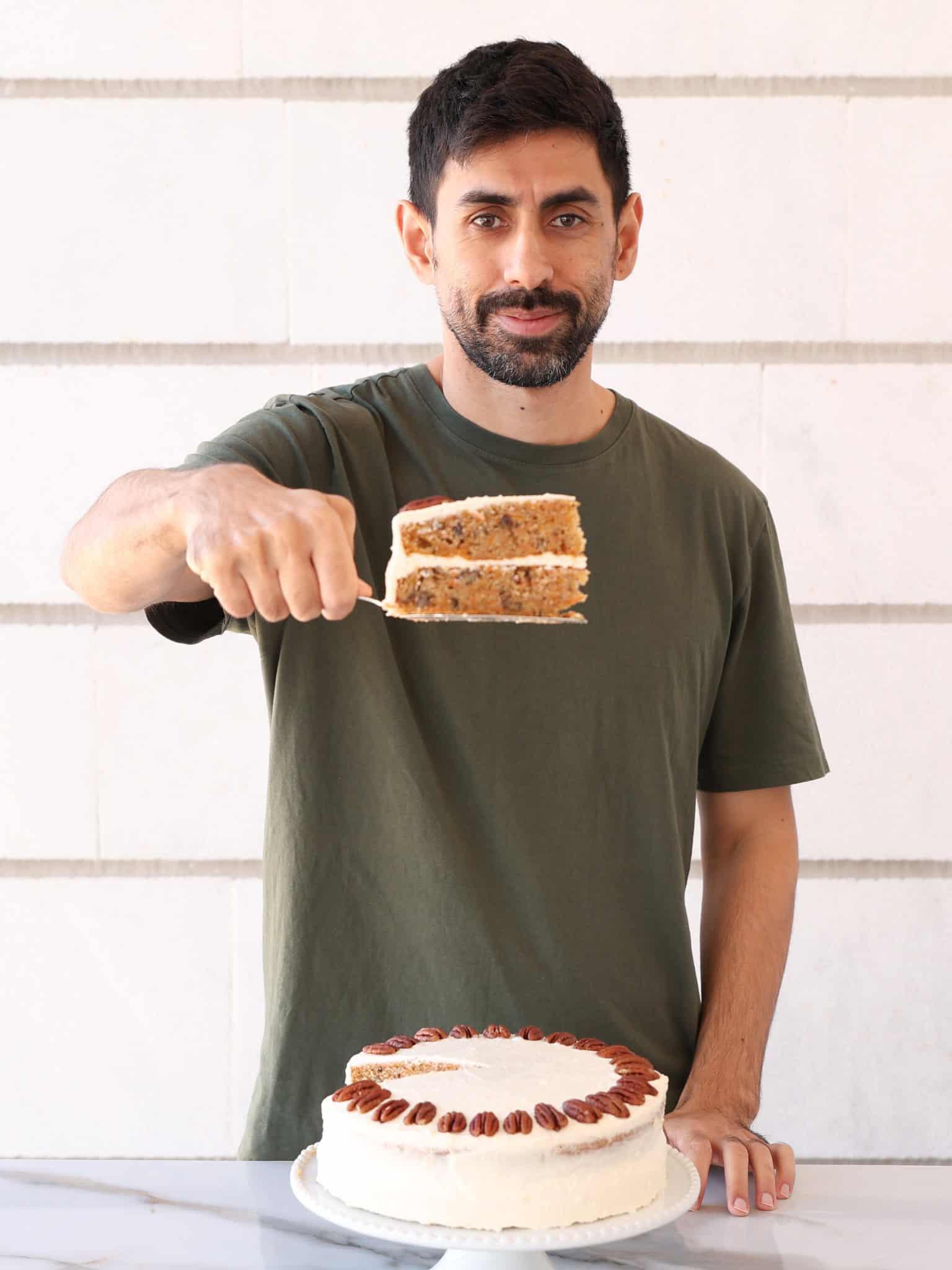 A person holding a slice of carrot cake sandwich.