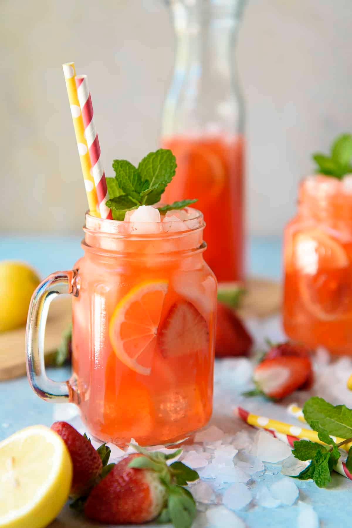 Close-up shot of a pitcher of strawberry lemonade with fresh strawberries and mint