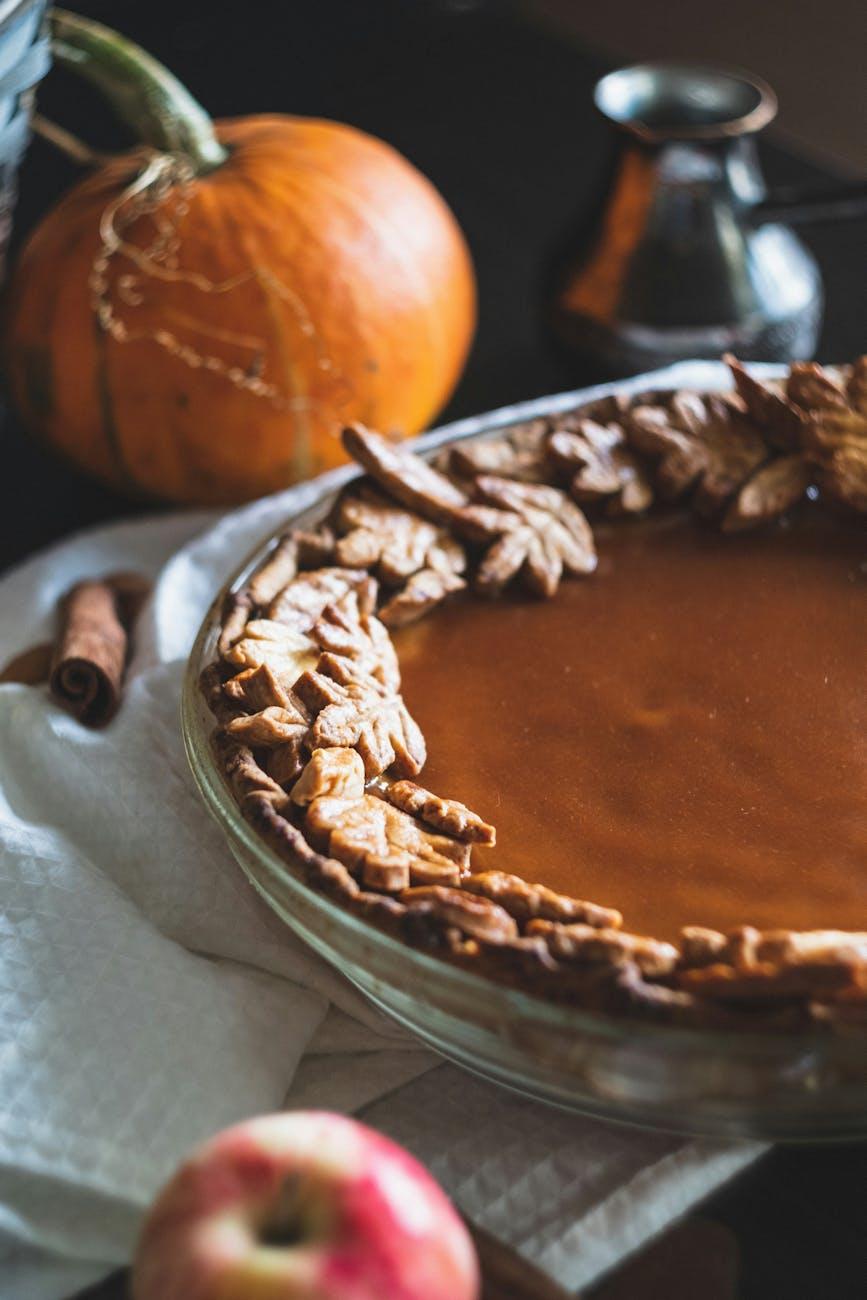 A rustic, golden-brown almond sweet potato pie on a wooden table with autumn leaves
