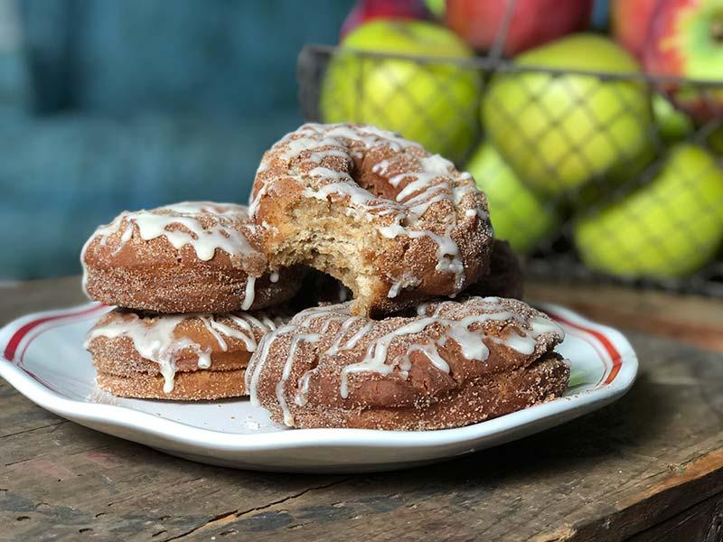 A plate of apple cider donuts with a side of maple syrup